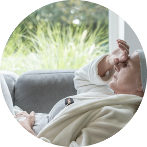 Sick senior with a hand on a forehead lying on a sofa.